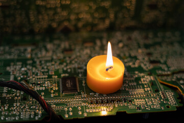 Burning candle on an electronic board. Lack of electricity due to war in Ukraine