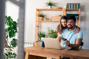 Happy smiling couple using bank card to shop online from home.