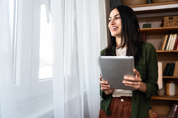 Attractive woman working on a digital tablet in a home office. Businesswoman small company owner...