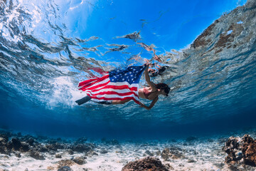 Freediver swims in tropical sea with United States flag. Independence day concept.