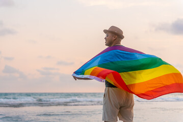 Young asian man with pride movement LGBT wrapped in rainbow flag for freedom. Demonstrate rights...