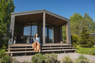 A woman sits on the terrace of a barnhouse. Wooden secluded house in Scandinavian and Finnish modern style