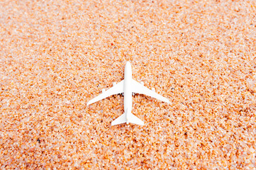 Miniature commercial airplane photographed from above isolated on golden beach sand background. Travel adventure concept. Vacation summer