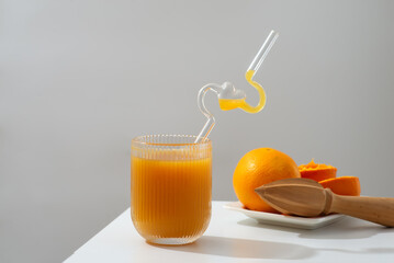 A glass of refreshing orange juice placed beside a plate of fresh oranges