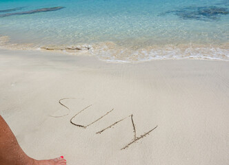 The word sun written in the sand on the beach in front of the sea