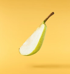 Fresh ripe Pear falling in the air, isolated on yellow background. Food levitation or zero gravity concept. High resolution image