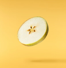 Fresh ripe Pear falling in the air, isolated on yellow background. Food levitation or zero gravity...