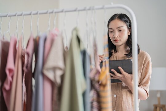 Asian Woman holding digital tablet in small cloth shop Online store selling or e-commerce
