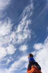 A man stands in the sky looking up at the clouds