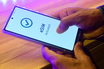 Mobile phone in hand displaying the message eSIM activated. Digital SIM to allow cellular...