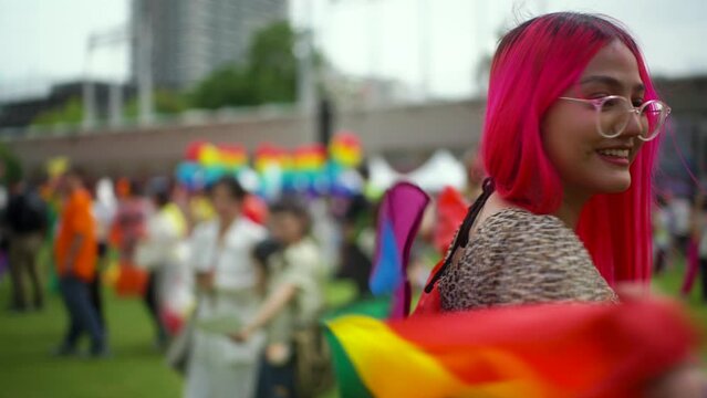 Happy moment LGBTQ female with pink hair celebration moment on Pride month Parade of LGBT community. Bisexual lesbian women Pride Parade with rainbow flag. LGBT and homosexual concept.
