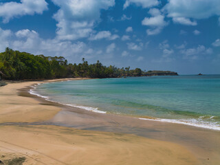 A deserted sandy beach on the island of Tobago in the Caribbean. Taken on a sunny day with light clouds.