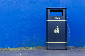 Black litter bin against blue wall in Glasgow
