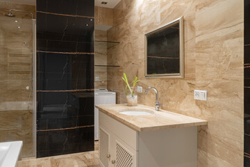 A luxurious bathroom featuring elegant marble walls, a modern vanity, and a spacious shower with...