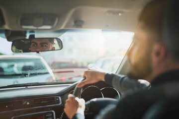 Hands, steering wheel and man in a car for road trip, transport and traffic jam navigation in a city. Travel, chauffeur and taxi driver in vehicle for cab, service and commute on highway journey