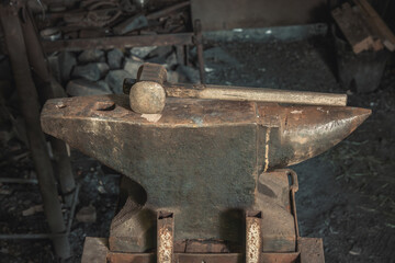 Rusty blacksmith's anvil and hammer in an abandoned workshop. Close-up