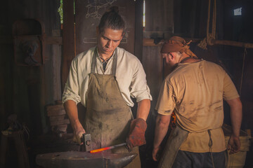 Blacksmith forges a red-hot metal piece on an anvil in a forge. Traditional crafts