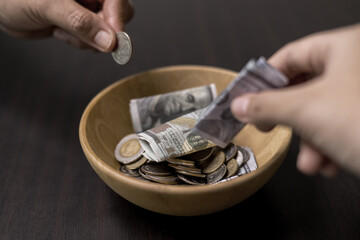 She felt deep sense of fulfillment when donating money to church, placing her tithe of coins and cash into offering bowl, knowing her giving would help fund important causes. donating, money, tithe.