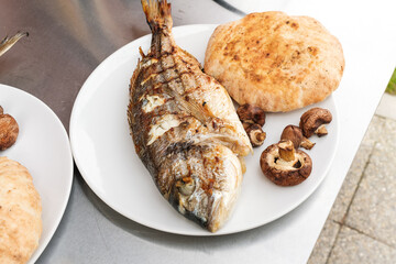 Gegrillte Goldbrasse mit Pitabrot und Champignons am Teller