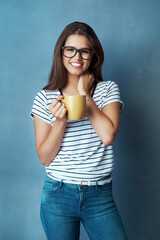 Happy woman, portrait and glasses with coffee in fashion for morning beverage, drink or caffeine on a blue studio background. Female person, nerd or geek with smile or mug for latte or cappuccino