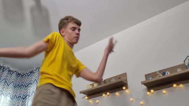 Teenage boy dancing energetically indoors, showcasing expressive moves and enjoying the music.