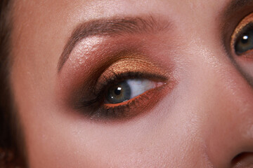 Obraz premium Evening warm golden brown and orange arabic shimmery eye makeup. close up on eye. Macro with glitter effect