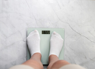 Feet in white socks stand on scales. Weight loss and diet concept.