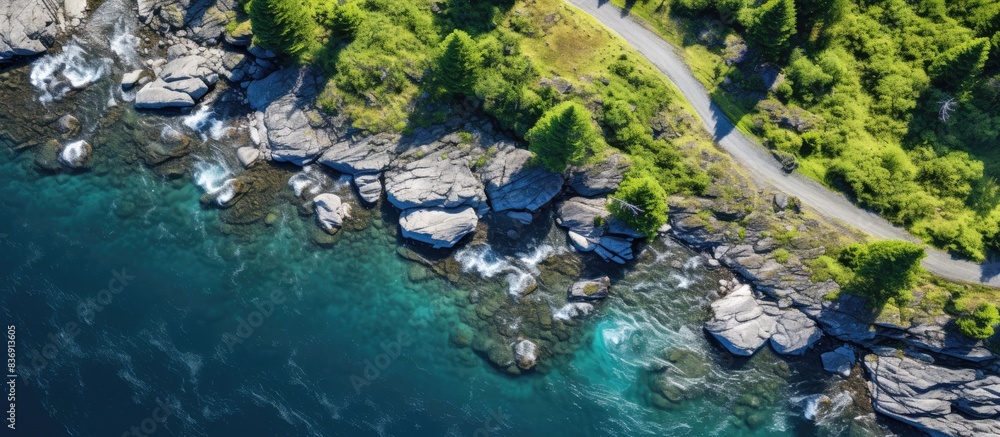Poster aerial drone captures a strong, clear mountain river winding through a stone-lined coast and lush fo