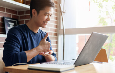 Fototapeta premium close up asian employee make gesture hand about help sign language to meeting and talking with team from webinar in home for office culture lifestyle concept