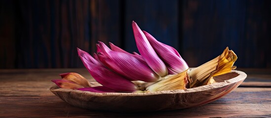 Banana blossom on a rustic wooden plate with copy space image. Rich in nutrients, the edible banana flower is a healthy, vegetarian option that promotes blood nourishment.