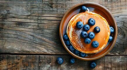 Plate of pancakes with fresh blueberries on a wooden table, top view. - Powered by Adobe