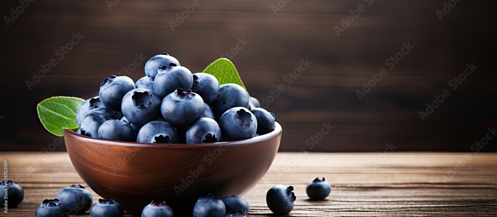 Poster Close up image of fresh blueberries in a small bowl on a wooden table with copy space image.