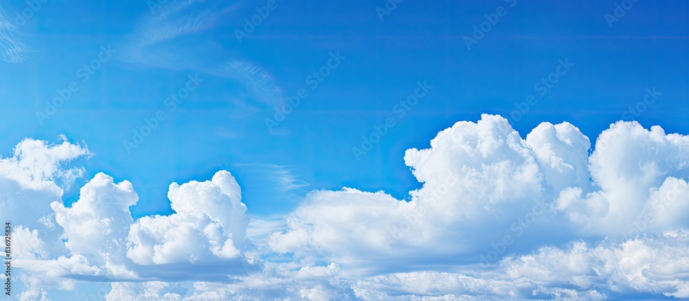 Poster background of a clear blue sky dotted with small fluffy clouds offers ample copy space image.