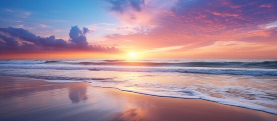 Fototapeta premium Scenic beach sunset reflecting in the ocean with a bright and vibrant sky, providing a beautiful view with copy space image.