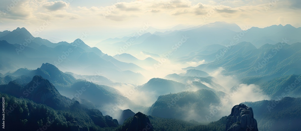 Poster Mountain landscape at dawn with misty clouds and rocks in the foreground, perfect for a copy space image.