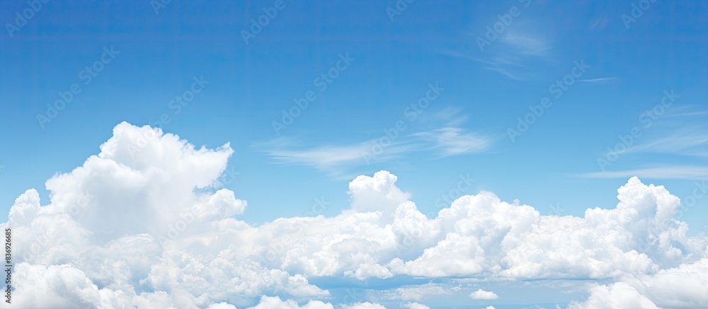 Poster fluffy white clouds dotting the clear blue sky offer a serene view for a copy space image.