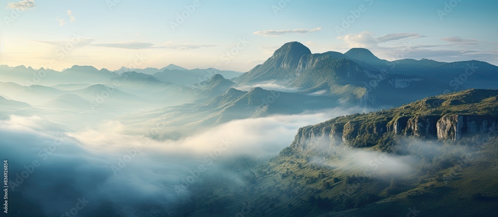 Poster Mountain landscape at dawn with misty clouds and rocks in the foreground, perfect for a copy space image.