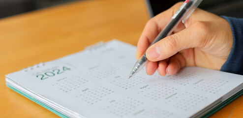 close up hand with pencil writing on calendar to mark date and detail about meeting and specify time of appointment for business concept