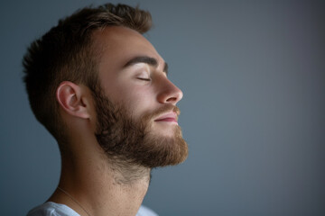 A close up of a man with beard and closed eyes looking to a side