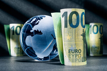 Blue globe with one hundred euro banknotes against a dark background