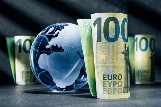Blue globe with one hundred euro banknotes against a dark background