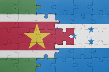 puzzle with the colourful national flag of honduras and flag of suriname