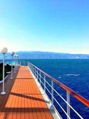 Luxury cruise ship deck. Large cruise liner ship sailing across mediterranean sea. Wooden cruise boat ship deck in sunset. Beautiful view on cruise ship deck. Floating liner vocation travel landscape
