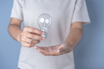 Close-up of both women's hands Holding a light bulb, innovative technology in science and...
