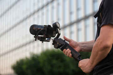 A man operating camera mounted on a gimbal, focus on the gimbal and camera
