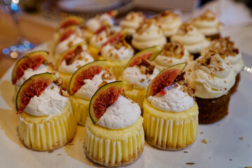 A plate full of small cupcakes with cream and fig pieces toppings.