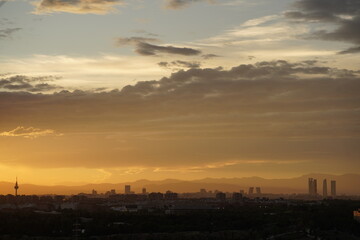 Atardecer, con horizonte de la ciudad de Madrid dejando ver la silueta de arquitectura y las montañas al fondo