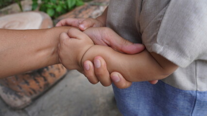 A harmonious family scene depicting a loving father holding his small and cute child's hand. The moment captures the bond and affection between the father and child, highlighting their close relations