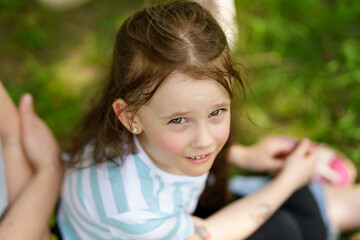 Portrait of a cute little girl sitting on a bench in the park