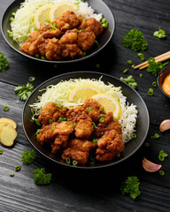 Japanese Fried crispy Chicken Karaage in black bowl with rice and cabbage